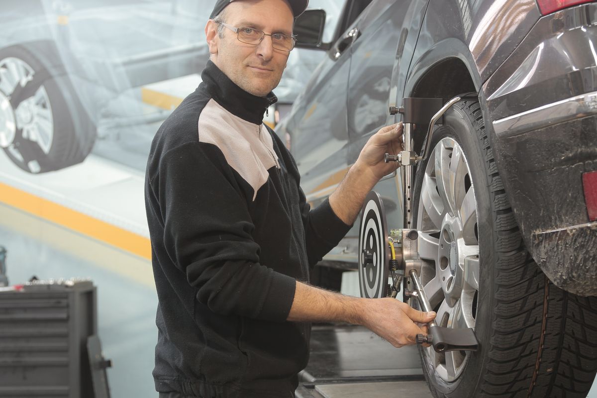 Mecânico fazendo cambagem e alinhamento da roda de um carro na Biguá Pneus Auto Center