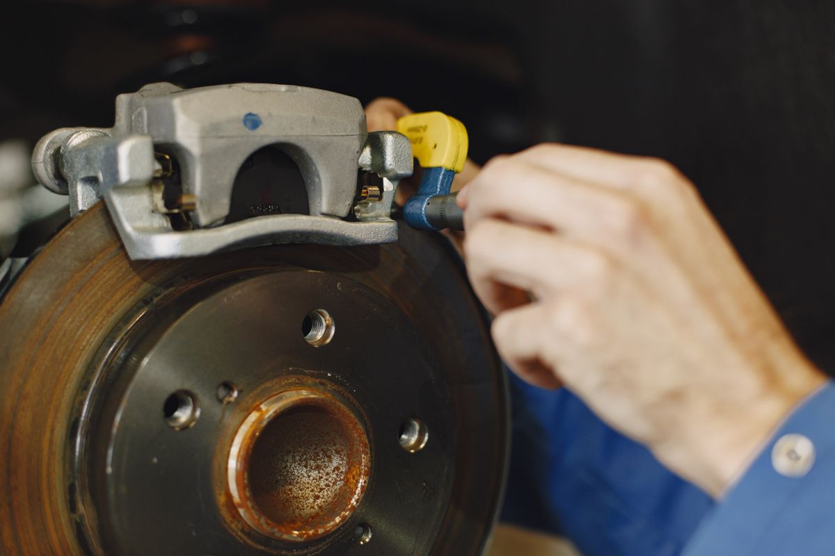 Mecânico trocando a pastilha de freio no disco de um carro na Biguá Pneus Auto Center